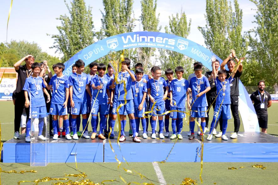 Torneo Internacional de Fútbol Madrid Football Cup U14 - Imagen del equipo gandador en el pódium celebrando la victoria, después de haber recibido el trofeo de ganador.