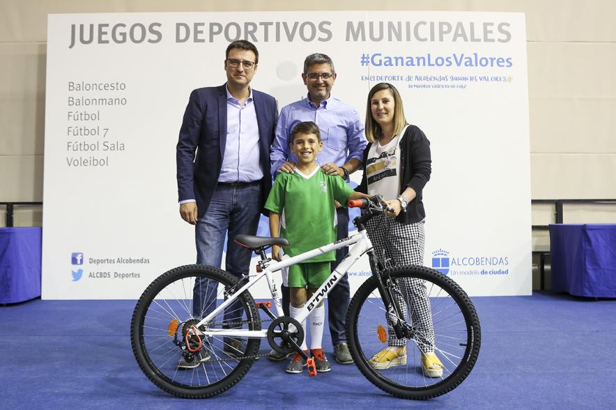 Entrega de trofeos XXII Juegos Deportivos Municipales - Posado de un deportista infantil con una bicicleta como premio junto a las autoridades municipales. 