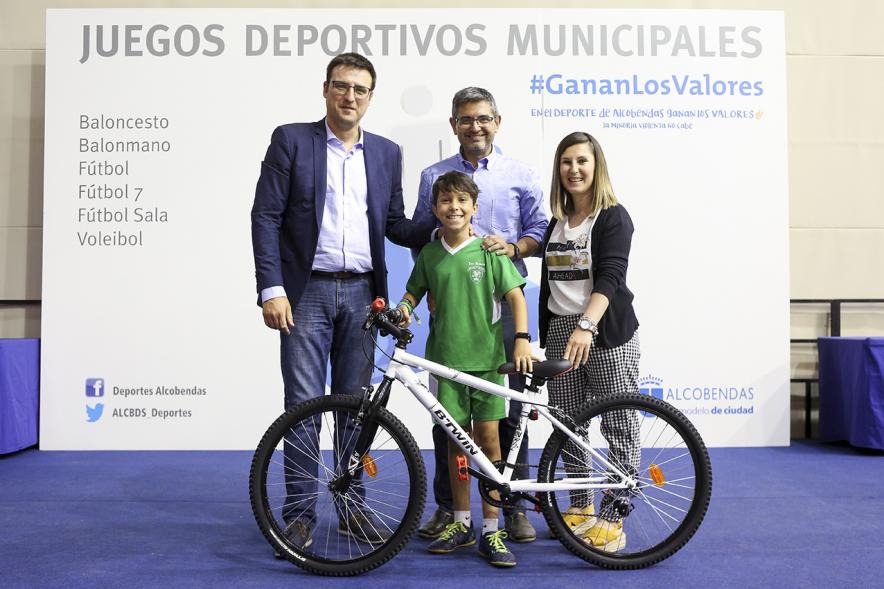 Entrega de trofeos XXII Juegos Deportivos Municipales -Posado de un deportista infantil con una bicicleta como premio junto a las autoridades municipales. 