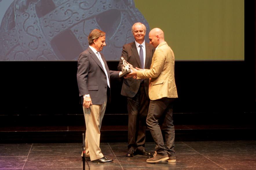 Gala XXº Aniversario FUNDAL - Imagen del alcalde García de Vinuesa entregando el obsequio de la Menina a un deportista en presencia de otra persona.