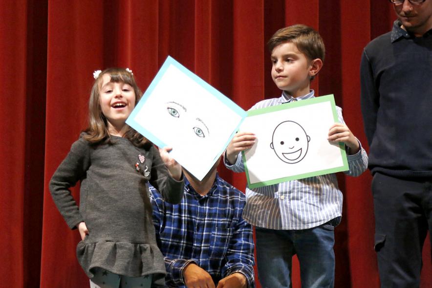 Gala APAMA 2019 -  Primer plano de dos niños enseñando unos carteles divertidos.