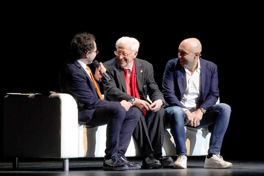 Gala Homenaje a la Solidaridad - Imagen del escenario, donde están sentados en un sofá charlando el mago More, el empresario Cipri Quintas y el padre Ángel.