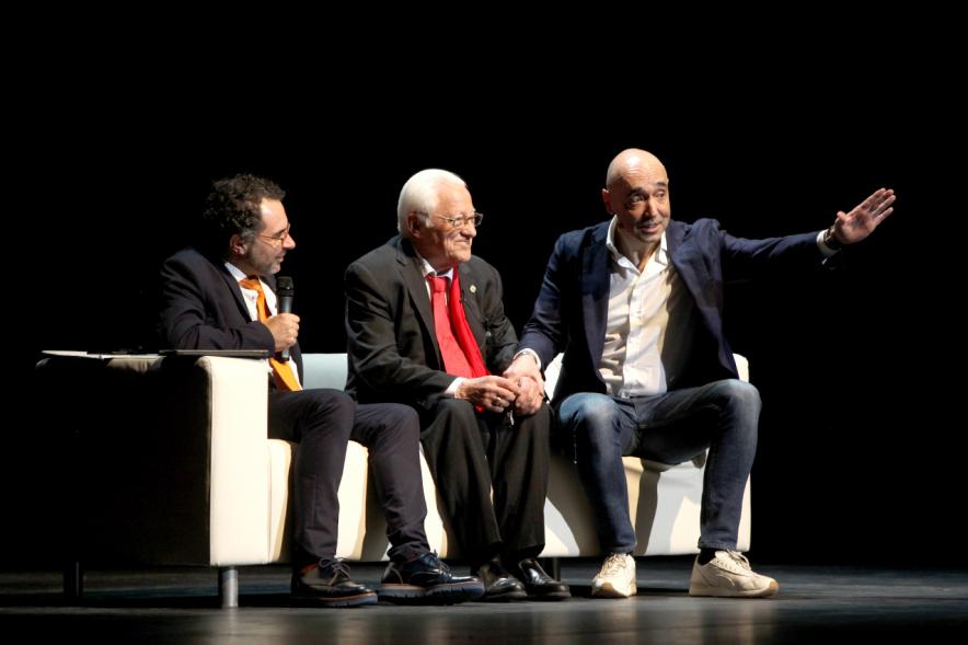 Gala Homenaje a la Solidaridad - Imagen del escenario, donde están sentados en un sofá charlando el mago More, el empresario Cipri Quintas y el padre Ángel.