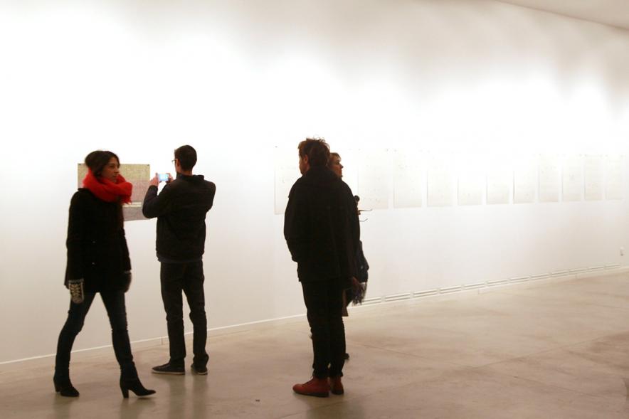Inauguración Exposición de Gonzalo Elvira "12 Canciones Concretas" - Imagen de persona mirando los cuadros de la exposición.