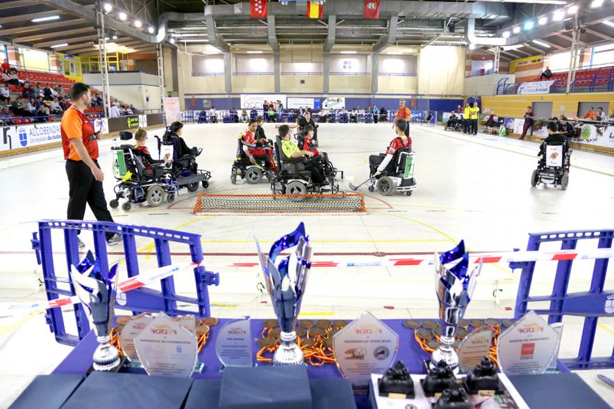Campeonato de España de Selecciones Autonómicas de Hockey en Silla de Ruedas - Primer plano de los trofeos y parte del partido.