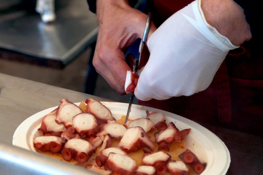 Inauguración XXIª Romería del Pulpo y el Mejillón - Imagen primer plano de una persona cortando el pulpo.