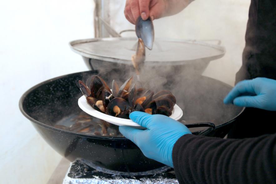 Inauguración XXIª Romería del Pulpo y el Mejillón - Imagen de persona colocando unos mejillones en un plato.