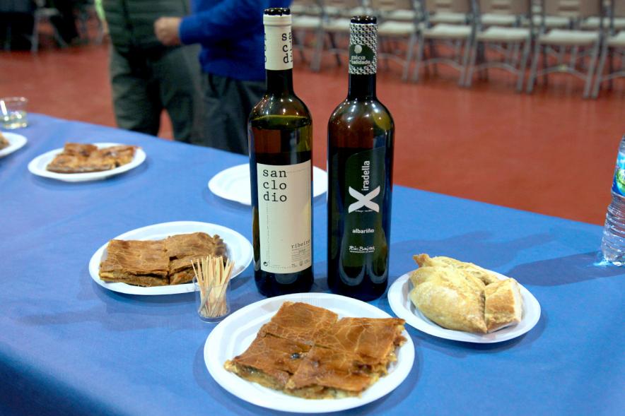 Inauguración XXIª Romería del Pulpo y el Mejillón - Imagen de una mesa donde hay unos platos de empanada, pan y botellas de vino.