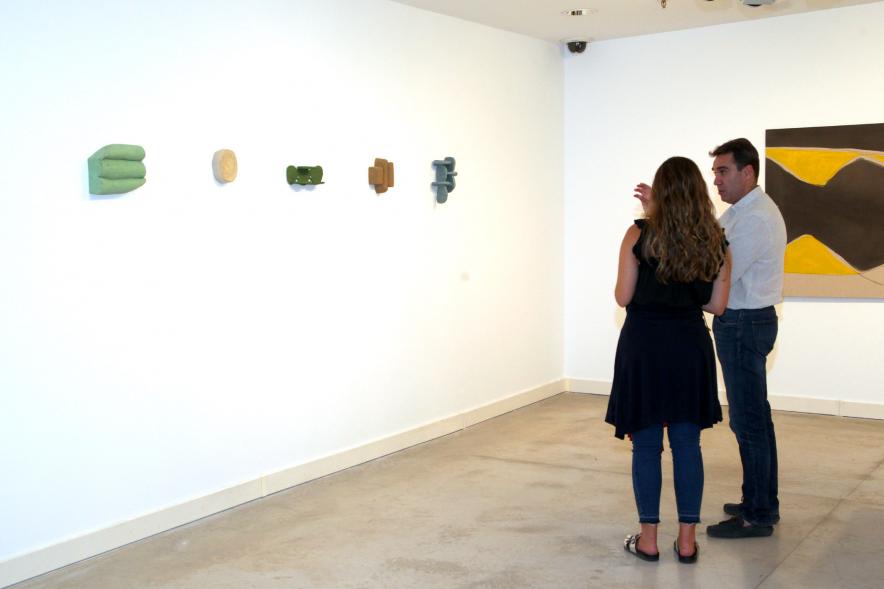 Inauguración de las Exposiciones "El camino Indicado" de Eduardo Barco y "Cocodrilos en la Pista - Estudio para una pieza Camp" de Miki Leal - Imagen de dos visitantes frente a un conjunto de obras pequeñas.