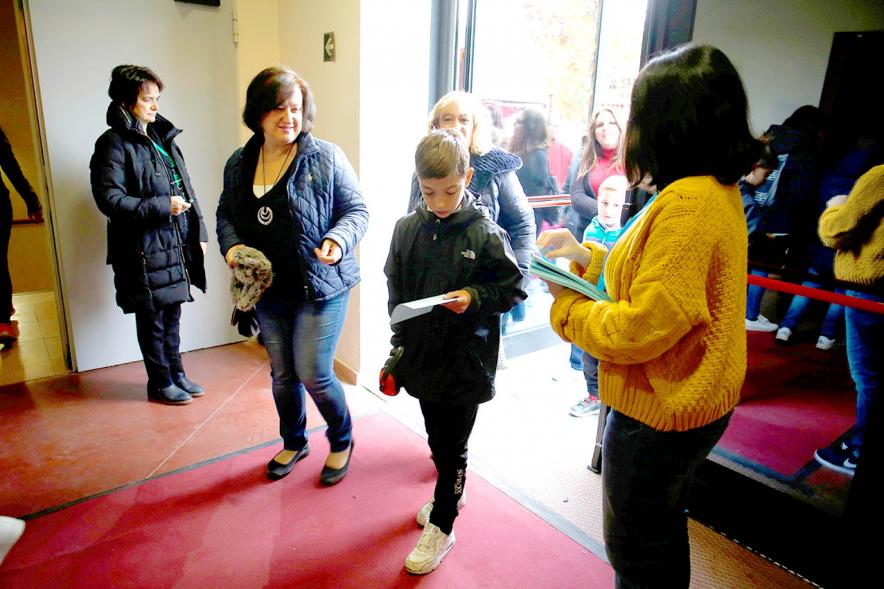 Fiesta Celebración Día Internacional de los Derechos de la Infancia - Imagen niño recogiendo  un programa a la entrada del evento.