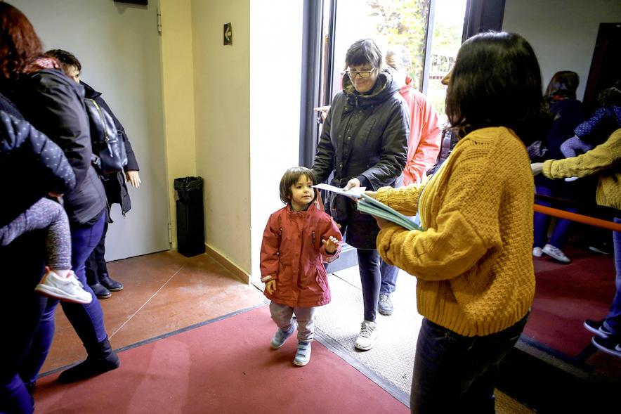 Fiesta Celebración Día Internacional de los Derechos de la Infancia - Imagen una familia recogiendo  un programa a la entrada del evento.