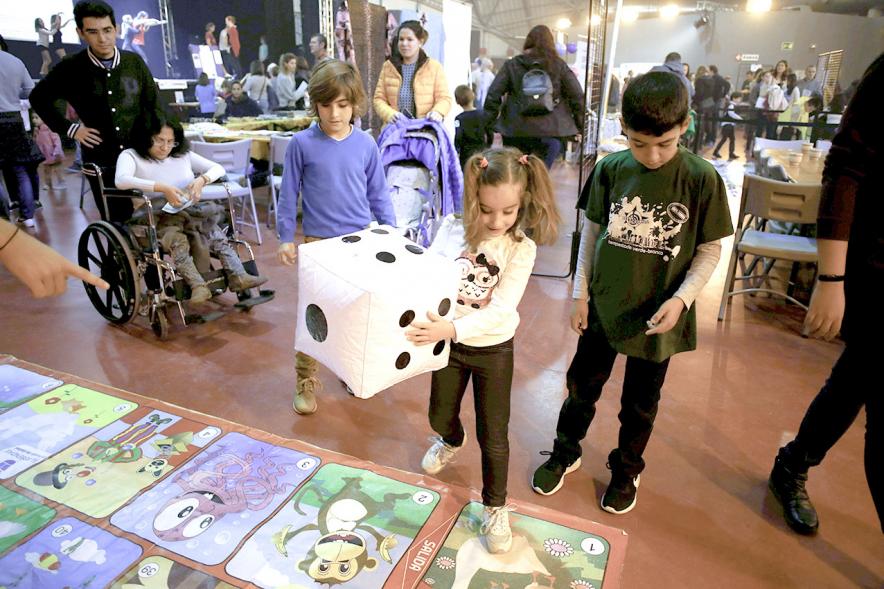 Fiesta Celebración Día Internacional de los Derechos de la Infancia - Imagen de un monitor jugando con unos niños al juego de la oca gigante.