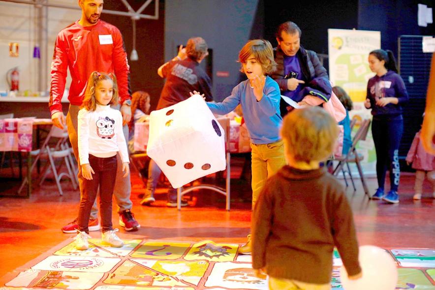Fiesta Celebración Día Internacional de los Derechos de la Infancia - Imagen de un monitor jugando con unos niños al juego de la oca gigante.
