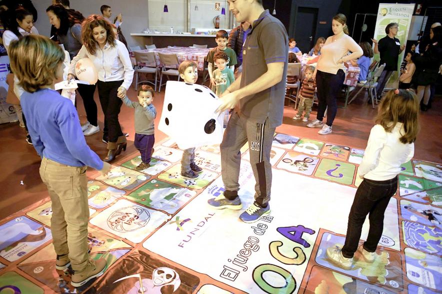 Fiesta Celebración Día Internacional de los Derechos de la Infancia - Imagen de un monitor jugando con unos niños al juego de la oca gigante.