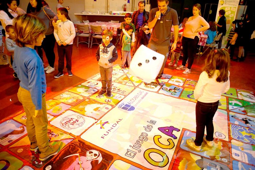 Fiesta Celebración Día Internacional de los Derechos de la Infancia - Imagen de un monitor jugando con unos niños al juego de la oca gigante.