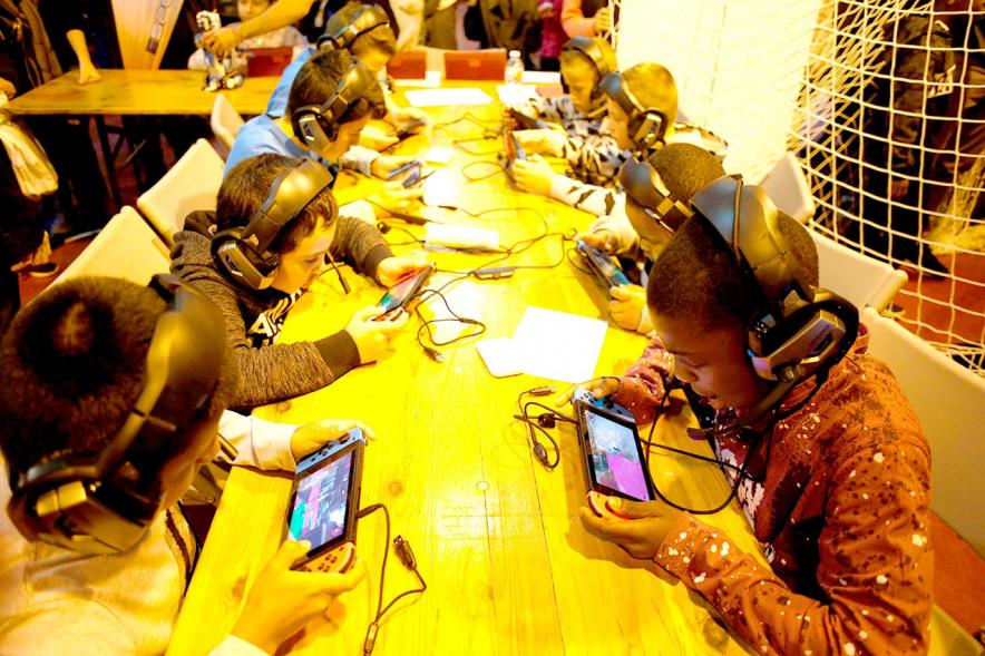 Fiesta Celebración Día Internacional de los Derechos de la Infancia - Imagen de unos niños jugando con video juegos en un stand.