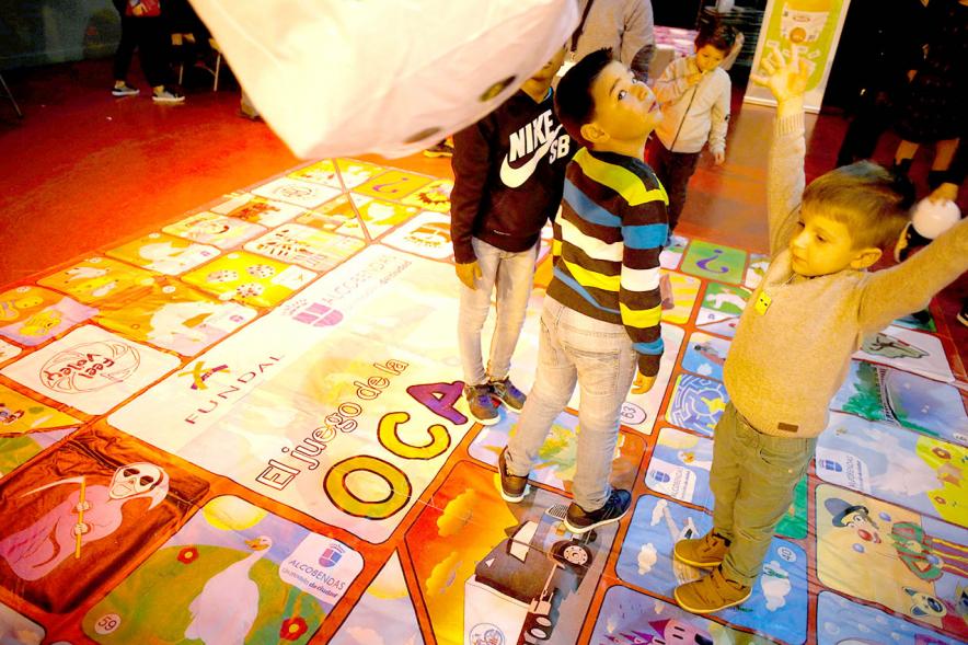 Fiesta Celebración Día Internacional de los Derechos de la Infancia - Imagen de un monitor jugando con unos niños al juego de la oca gigante.