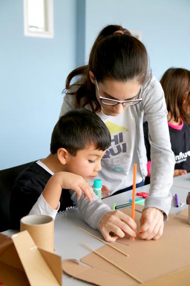 Día de la Nueva Participación Los Influyentes - Primer plano de la monitora ayudando a pintar a un niño.