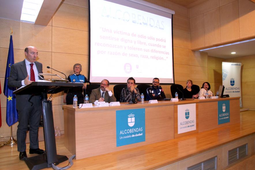 Clausura Jornada "Las Infracciones de Odio" - Imagen del escenario con una autoridad dirigiéndose al público asistente y los componentes de la mesa de debate.
