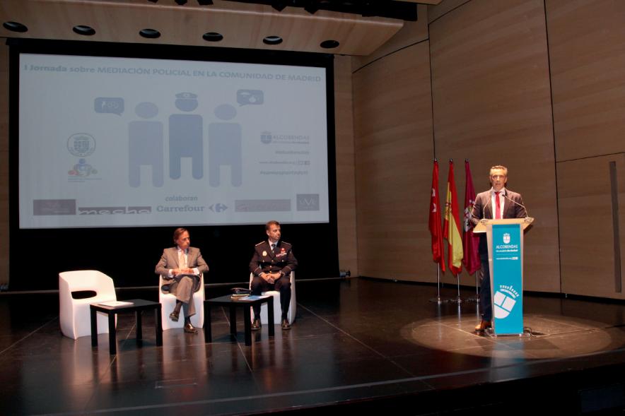 Iª Jornada sobre Mediación Policial en la Comunidad de Madrid - Imagen del escenario con el alcalde García de Vinuesa, el concejal y un mando de la policía municipal.