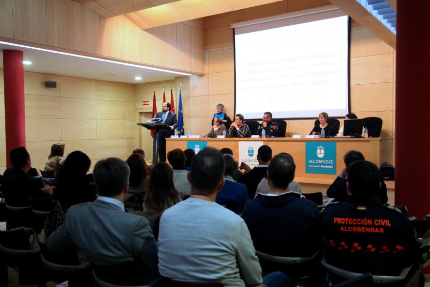 Clausura Jornada "Las Infracciones de Odio" - Imagen lejana del escenario con una autoridad dirigiéndose al público asistente y los componentes de la mesa de debate.