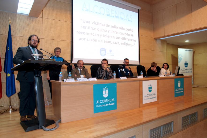 Clausura Jornada "Las Infracciones de Odio" - Imagen del escenario con una autoridad dirigiéndose al público asistente y los componentes de la mesa de debate.
