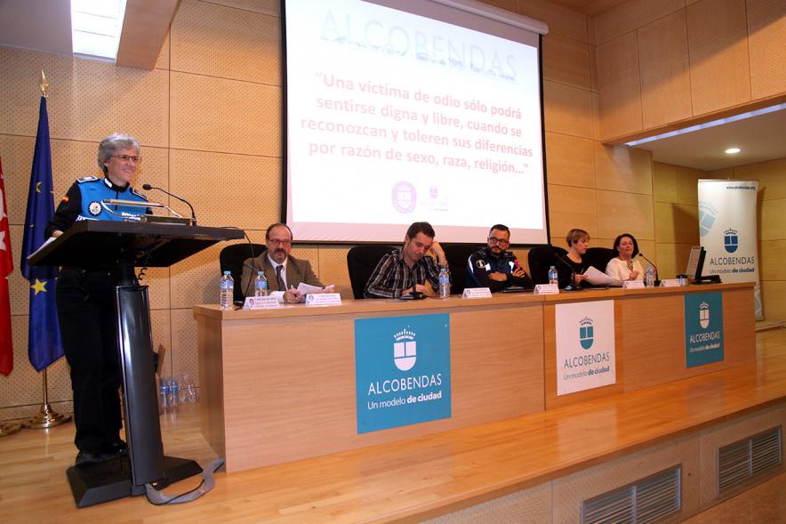 Clausura Jornada "Las Infracciones de Odio" - Imagen del escenario con un miembro de seguridad dirigiéndose al público asistente y los componentes de la mesa de debate.