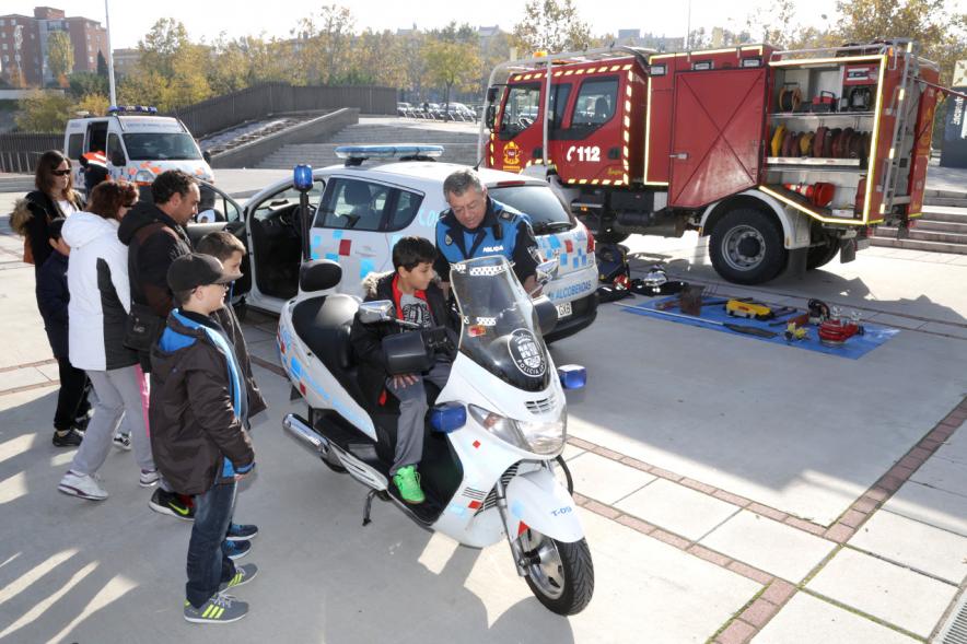 Jornada de Emergencias en Familia - Imagen de un miembro de un cuerpo de seguridad con un niño enseñándole una moto de policía.