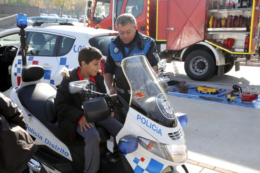 Jornada de Emergencias en Familia - Imagen de un miembro de un cuerpo de seguridad con un niño enseñándole una moto de policía.