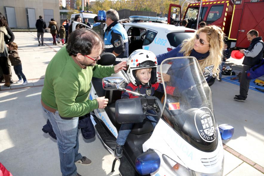 Jornada de Emergencias en Familia - Imagen de un miembro de un cuerpo de seguridad con un niño enseñándole una moto de policía.
