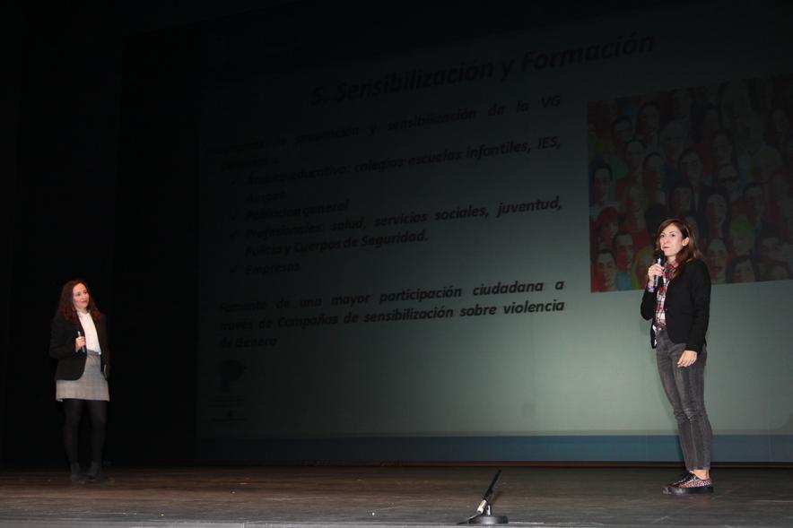 Jornada con los Institutos de Educación Secundaria Contra la Violencia de Género - Imagen de dos ponentes sobre  el escenario a media luz.