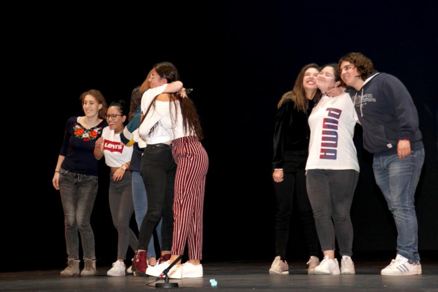 Jornada con los Institutos de Educación Secundaria Contra la Violencia de Género - Imagen del escenario con varias estudiantes abrazándose.