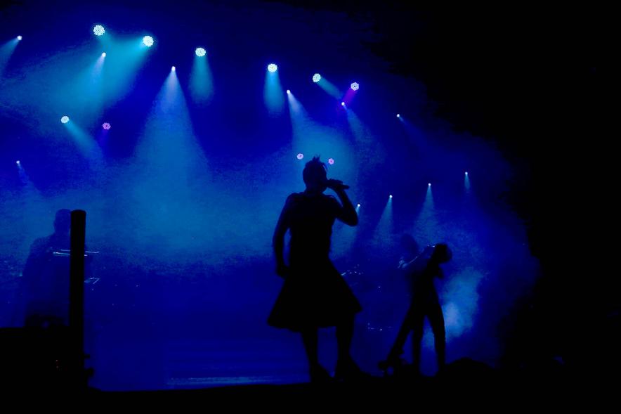 Cantantes a contra luz con fondo de focos azules
