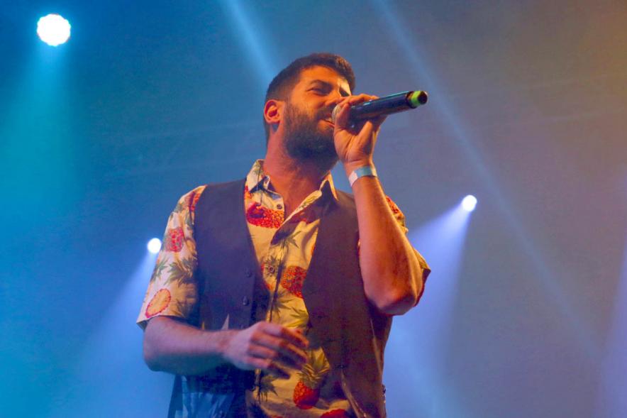 Cantante al micrófono bajo focos azulados