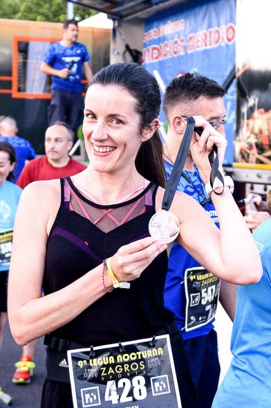 Legua Nocturna 2019 -  Imagen de una participante de la carrera mostrando su medalla.