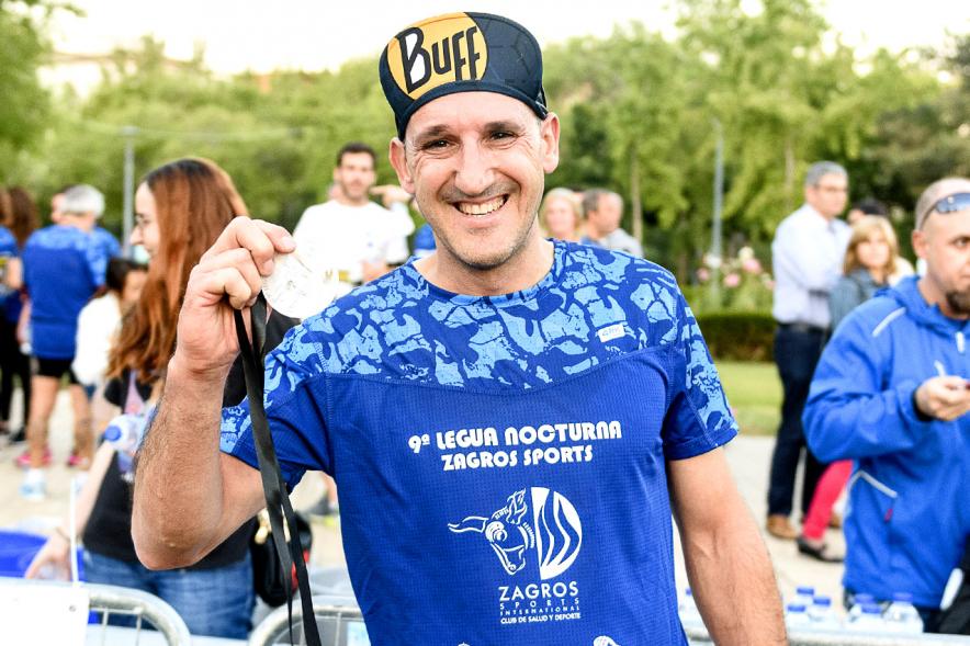Legua Nocturna 2019 - Imagen de un participante de la carrera con su medalla.
