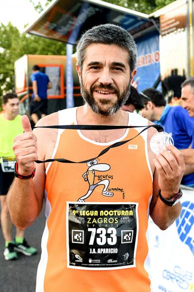 Legua Nocturna 2019 - Imagen de un participante de la carrera con su medalla.