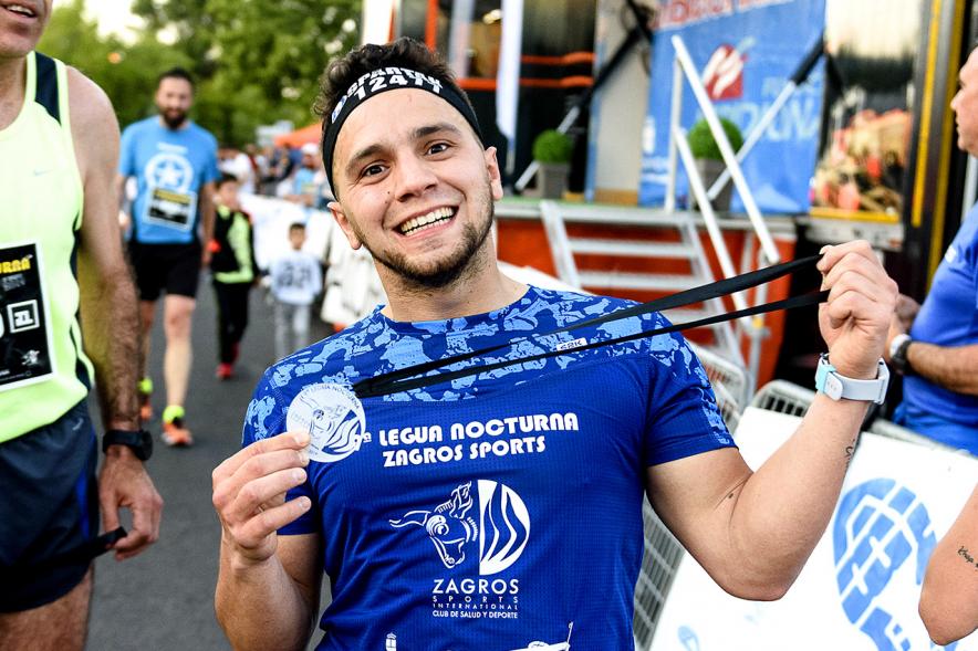 Legua Nocturna 2019 - Imagen de un participante de la carrera con su medalla.