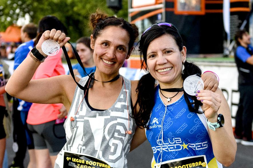 Legua Nocturna 2019 - Imagen de unas participantes de la carrera mostrando sus medallas.