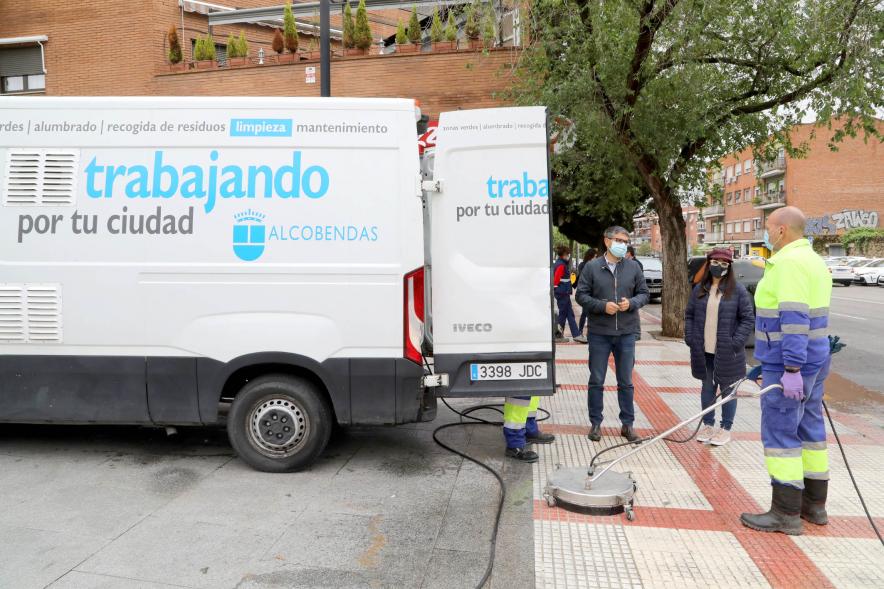 Operario de limpieza usando maquinaria mientras charla con delegación municipal