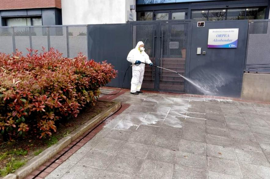 Operario con traje de protección desinfecta la entrada de una residencia de ancianos