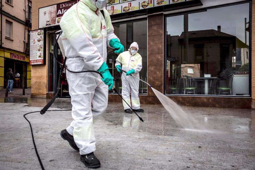 Operarios con traje de protección desinfectando las calles durante el confinamiento
