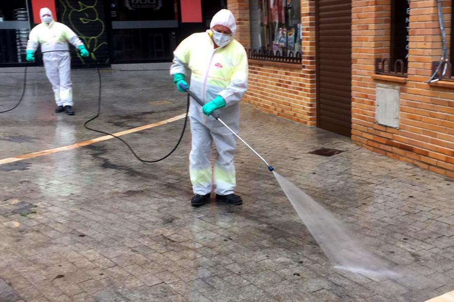 Operarios con traje de protección desinfectando las calles durante el confinamiento