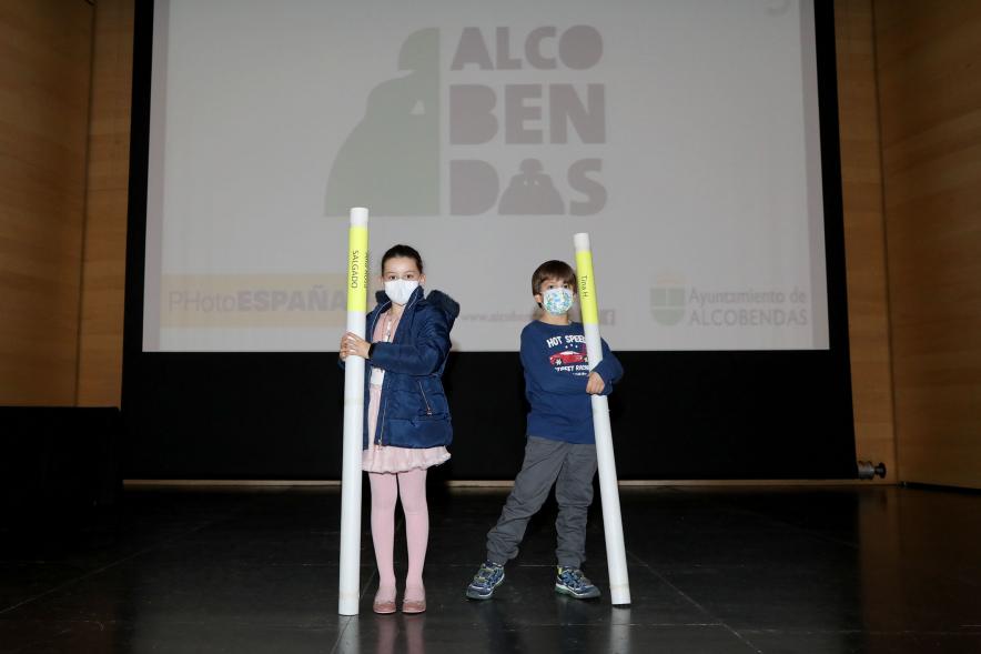 Entrega de Lonas Expo #PHEdesdemibalcon PHotoESPAÑA - Imagen de un nió y una niña en el escenario posando con las lonas que acaban de recibir.