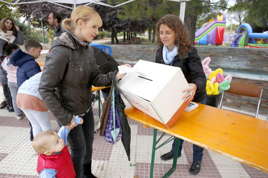 Proceso Participativo Elección de Luces Navideñas 2018 - Imagen  de las mesas con las urnas y una familia votando.