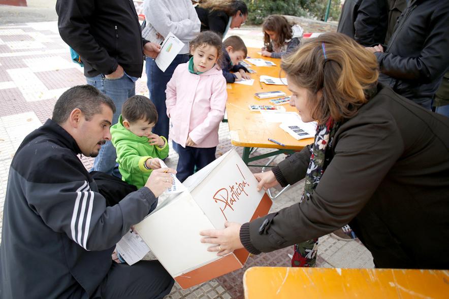 Proceso Participativo Elección de Luces Navideñas 2018 - Primer plano de la urna y una familia votando.