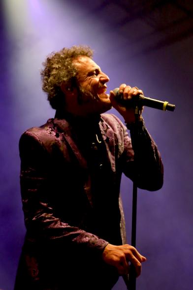 Cantante al micrófono bajo focos morados