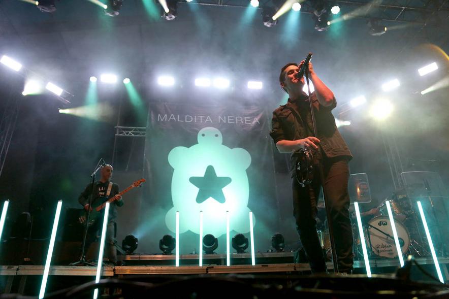 Cantante en el escenario con logo del grupo al fondo