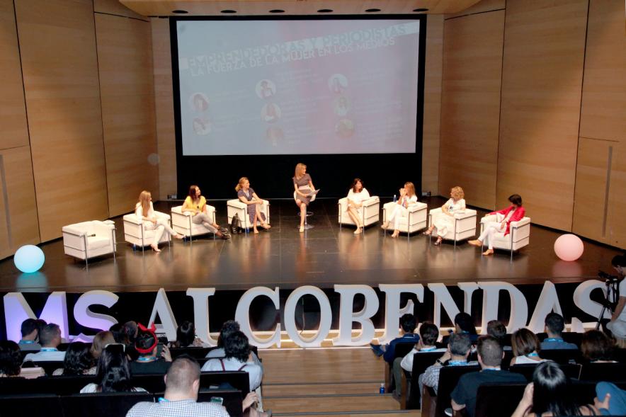 Media StartUps Alcobendas - Panorámica del escenario con las ponentes sentadas y parte del anfiteatro lleno.