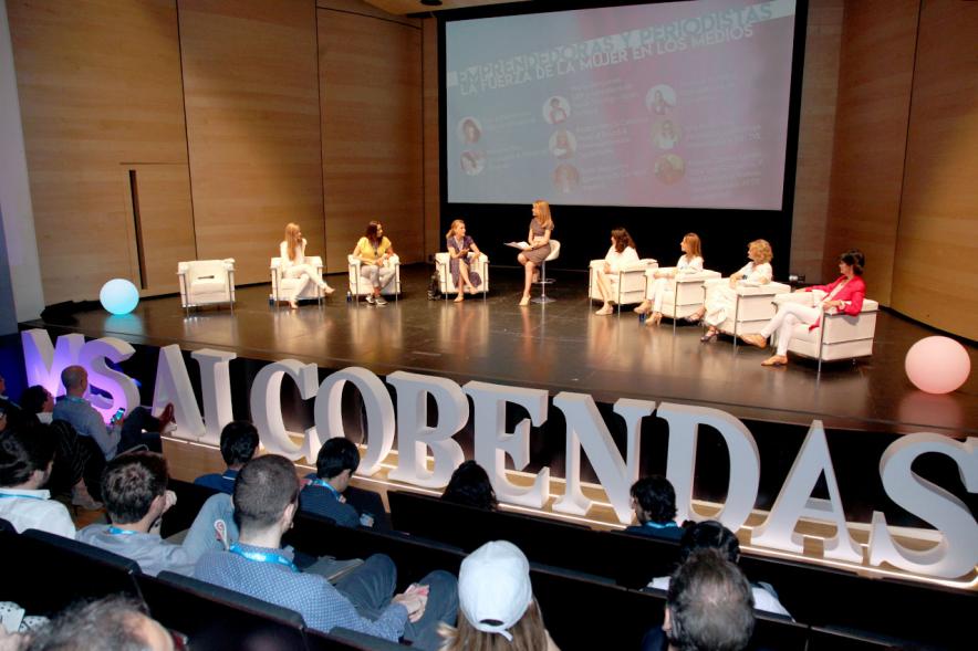 Media StartUps Alcobendas - Panorámica del escenario con las ponentes sentadas y el logotipo de la presentación.